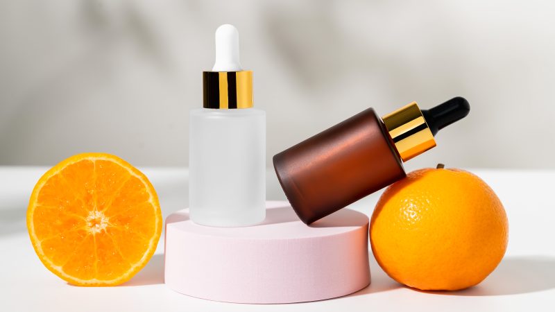 Serum bottle with dropper and slice of orange, ingredients for skin care and treatment vitamin on white background, Natural cosmetics concept.