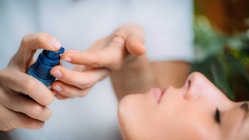 Retinol Treatment. Cosmetician Applying Retinol Serum on Woman’s Face