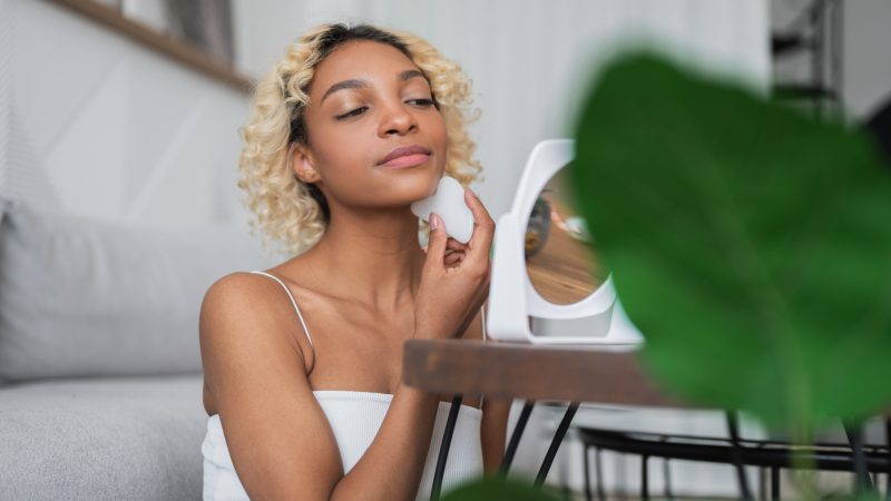 Woman doing gua sha face massage at home. Morning beauty skin care routine.