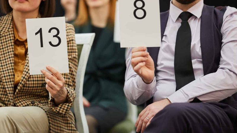 Close-up of business people sitting on chairs with signs with numbers and voting